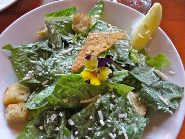 The ceasar salad is always served with a fresh violet on top.